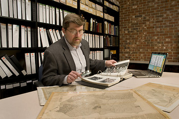 Image showing Researcher in archive, searching through maps and photographs