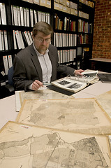 Image showing Researcher in archive, searching through maps and photographs.