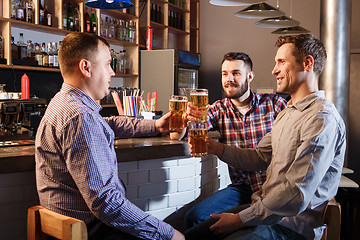 Image showing Happy friends drinking beer at counter in pub