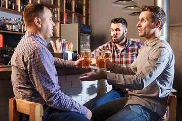 Image showing Happy friends drinking beer at counter in pub