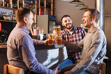 Image showing Happy friends drinking beer at counter in pub