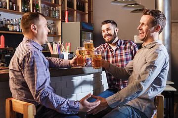 Image showing Happy friends drinking beer at counter in pub