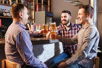 Image showing Happy friends drinking beer at counter in pub