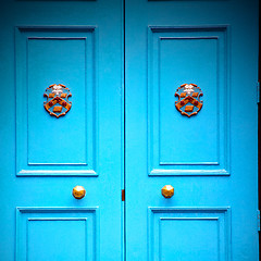 Image showing  blue handle in london antique brown door  rusty  brass nail and