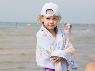 Image showing Three year old girl standing on the beach wrapped in a towel