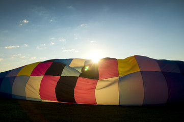Image showing Sun peaking over the inflating envelope of a hot air balloon