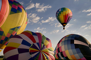 Image showing Hot air balloon floating over other inflating balloons