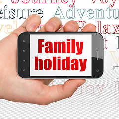 Image showing Travel concept: Hand Holding Smartphone with Family Holiday on display