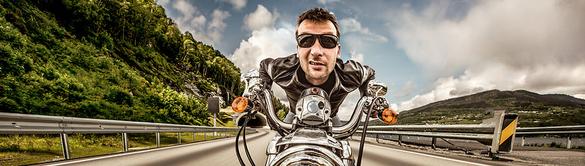 Image showing Funny Biker in sunglasses and leather jacket racing on mountain 