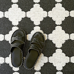 Image showing Leather sandals on black and white rug