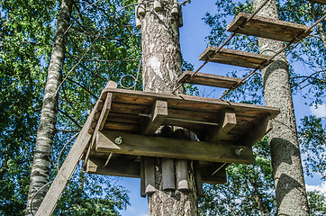 Image showing Dangerous ropeway with tether in rope park, trees with green lea