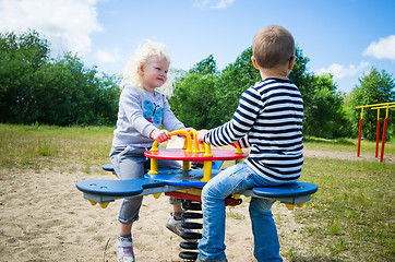 Image showing Boy and girl swinging on a swing