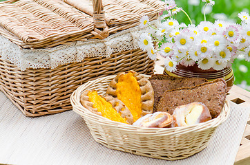 Image showing Buns in a wicker basket and a bouquet of flowers