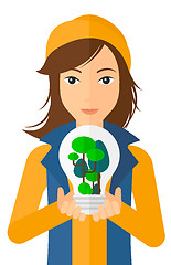 Image showing Woman with lightbulb and trees inside.