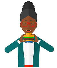 Image showing Woman eating hamburger. 