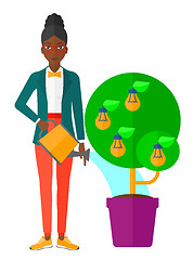 Image showing Woman watering tree with light bulbs.