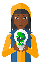 Image showing Woman with lightbulb and trees inside.