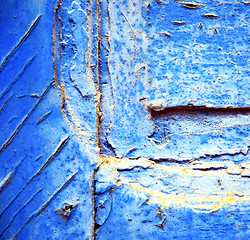 Image showing dirty stripped paint in the blue wood door and rusty nail