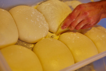 Image showing Small balls of fresh homemade pizza dough on floured wooden board 