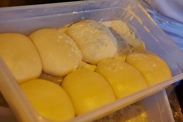 Image showing Small balls of fresh homemade pizza dough on floured wooden board 