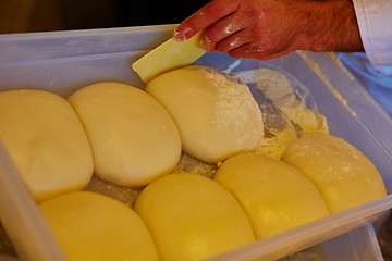 Image showing Small balls of fresh homemade pizza dough on floured wooden board 