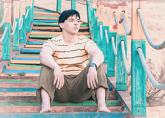 Image showing A young man sitting on the steps