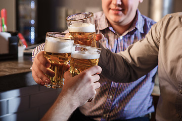 Image showing Happy friends drinking beer at counter in pub