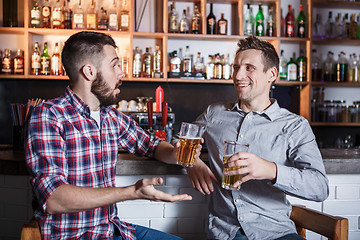 Image showing Happy friends drinking beer at counter in pub