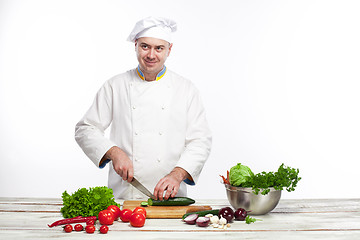 Image showing Chef cutting a green cucumber in his kitchen