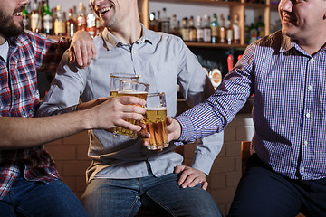 Image showing Happy friends drinking beer at counter in pub