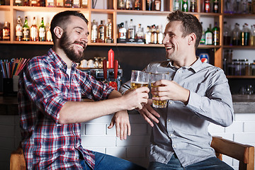 Image showing Happy friends drinking beer at counter in pub