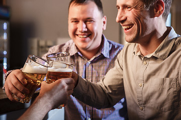 Image showing Happy friends drinking beer at counter in pub