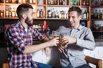 Image showing Happy friends drinking beer at counter in pub