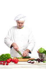 Image showing Chef cutting a green cucumber in his kitchen