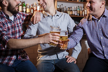 Image showing Happy friends drinking beer at counter in pub