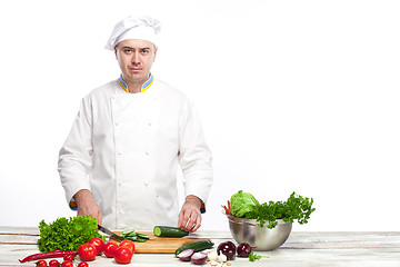 Image showing Chef cutting a green cucumber in his kitchen