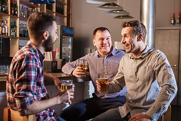 Image showing Happy friends drinking beer at counter in pub