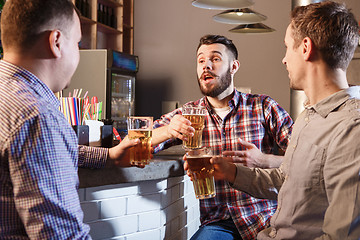 Image showing Happy friends drinking beer at counter in pub