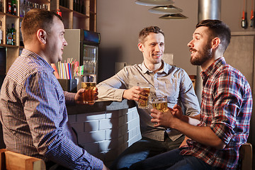 Image showing Happy friends drinking beer at counter in pub