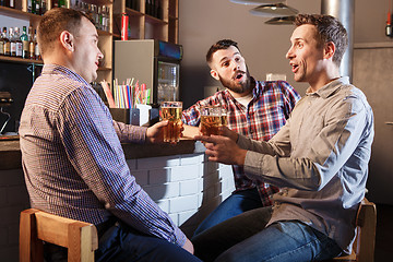 Image showing Happy friends drinking beer at counter in pub