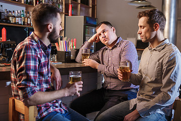 Image showing The  friends drinking beer at counter in pub