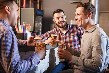 Image showing Happy friends drinking beer at counter in pub