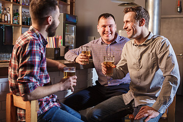 Image showing Happy friends drinking beer at counter in pub