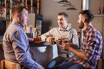 Image showing Happy friends drinking beer at counter in pub