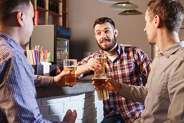 Image showing Happy friends drinking beer at counter in pub