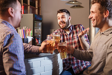 Image showing Happy friends drinking beer at counter in pub