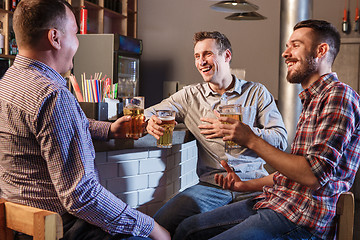 Image showing Happy friends drinking beer at counter in pub