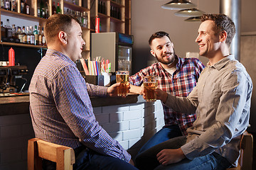 Image showing Happy friends drinking beer at counter in pub