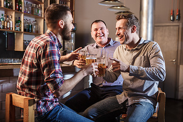 Image showing Happy friends drinking beer at counter in pub