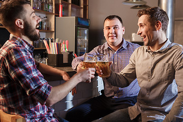 Image showing Happy friends drinking beer at counter in pub